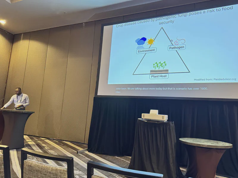 A speaker presenting a plant-trait diagram at a conference.
