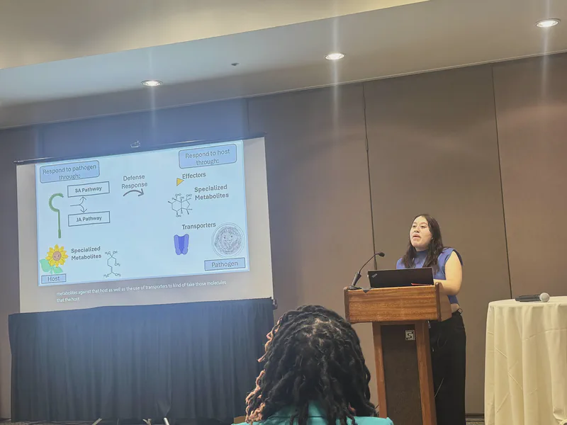 A researcher presenting diagrams of plant and microbial interactions.