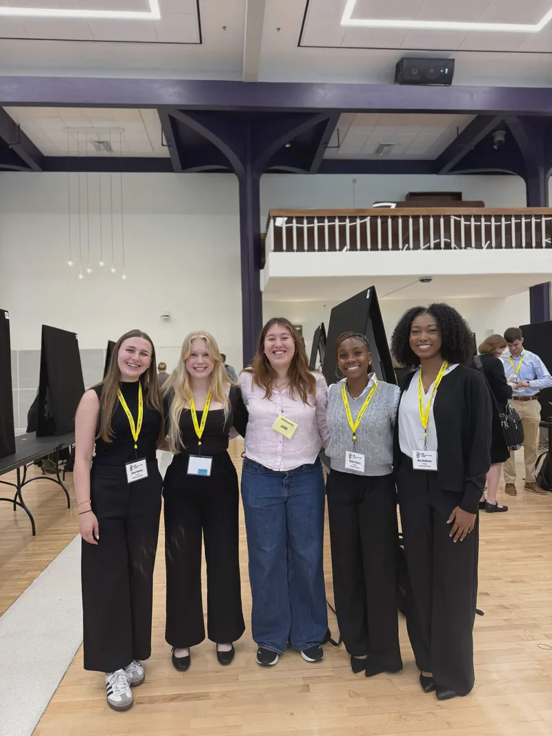 Five students wearing presenter medals at a poster exhibition.