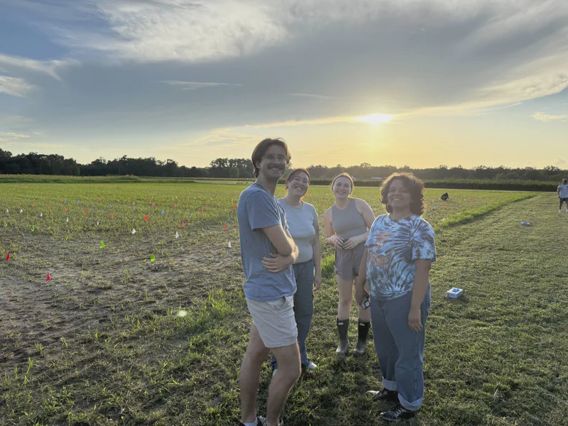 Three lab members smiling in a field at sunset.
