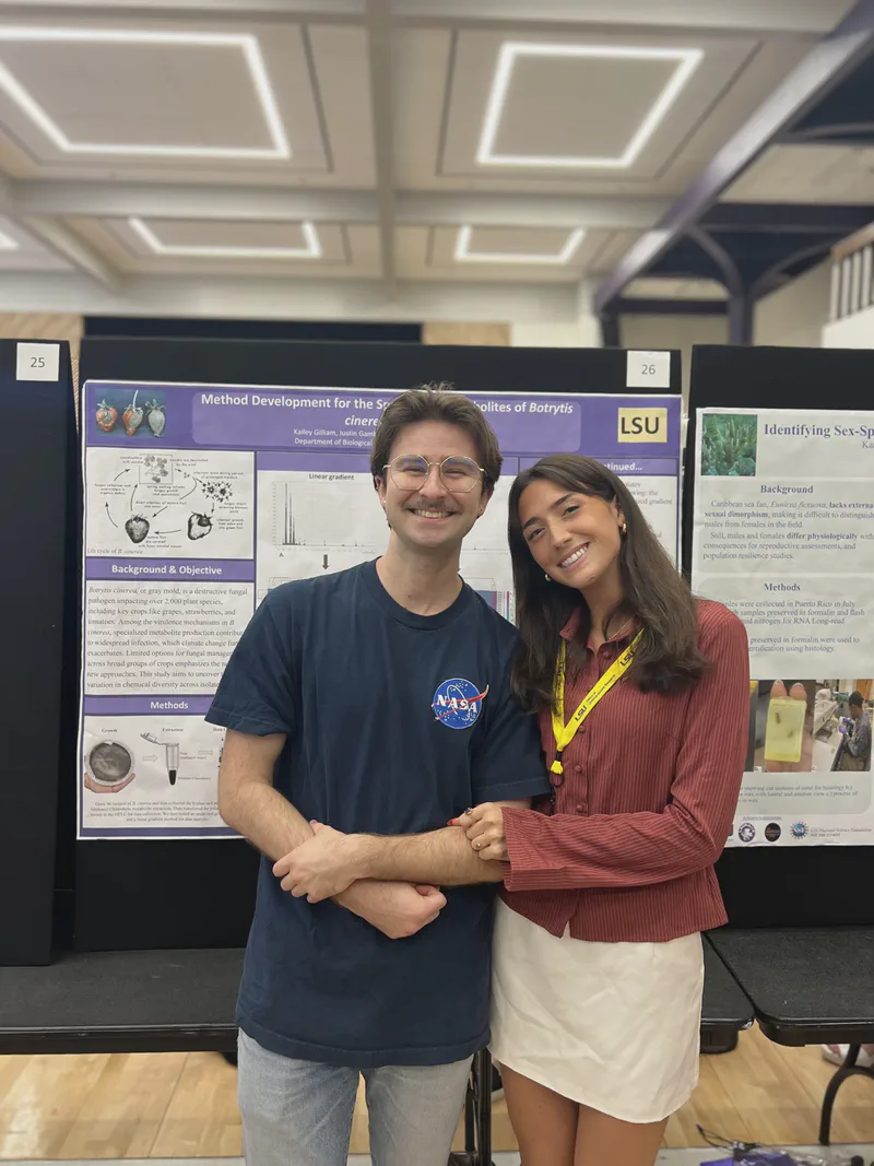 Two researchers standing together in front of a student poster.