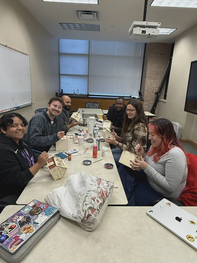 Lab members smiling around a table with food and gifts.